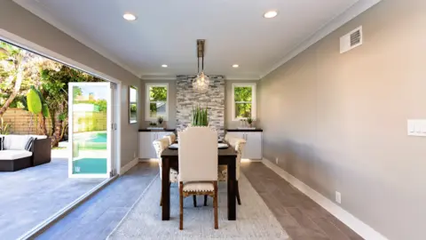 A freshly painted dining room in soft greys, opening onto a pool terrace